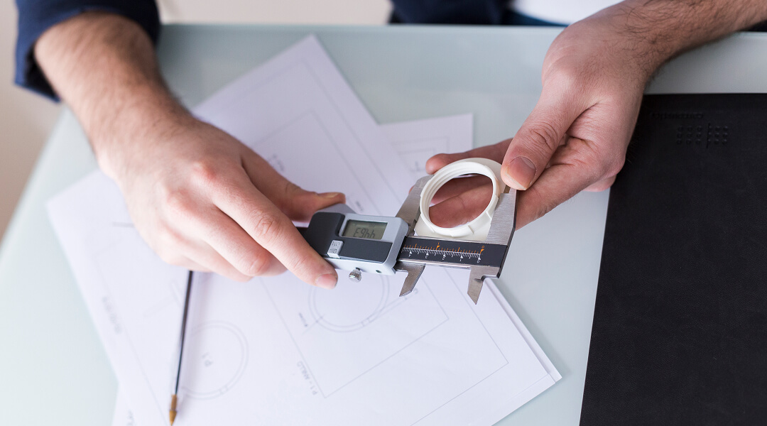 Un homme tient un pied à coulisse tout en travaillant sur un projet technique.